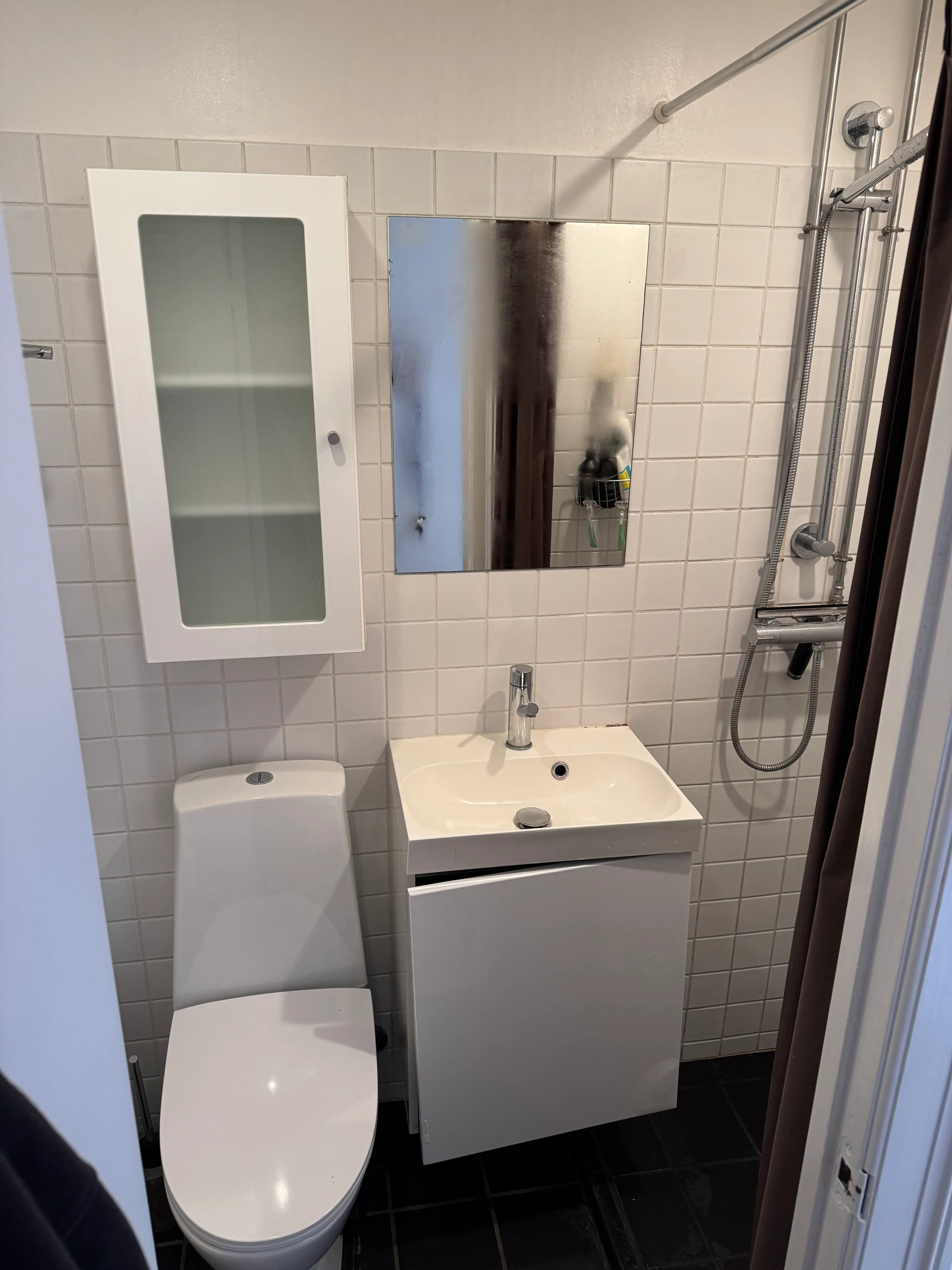 Original bathroom vanity, sink and separate mirror before replacement in a compact tiled bathroom