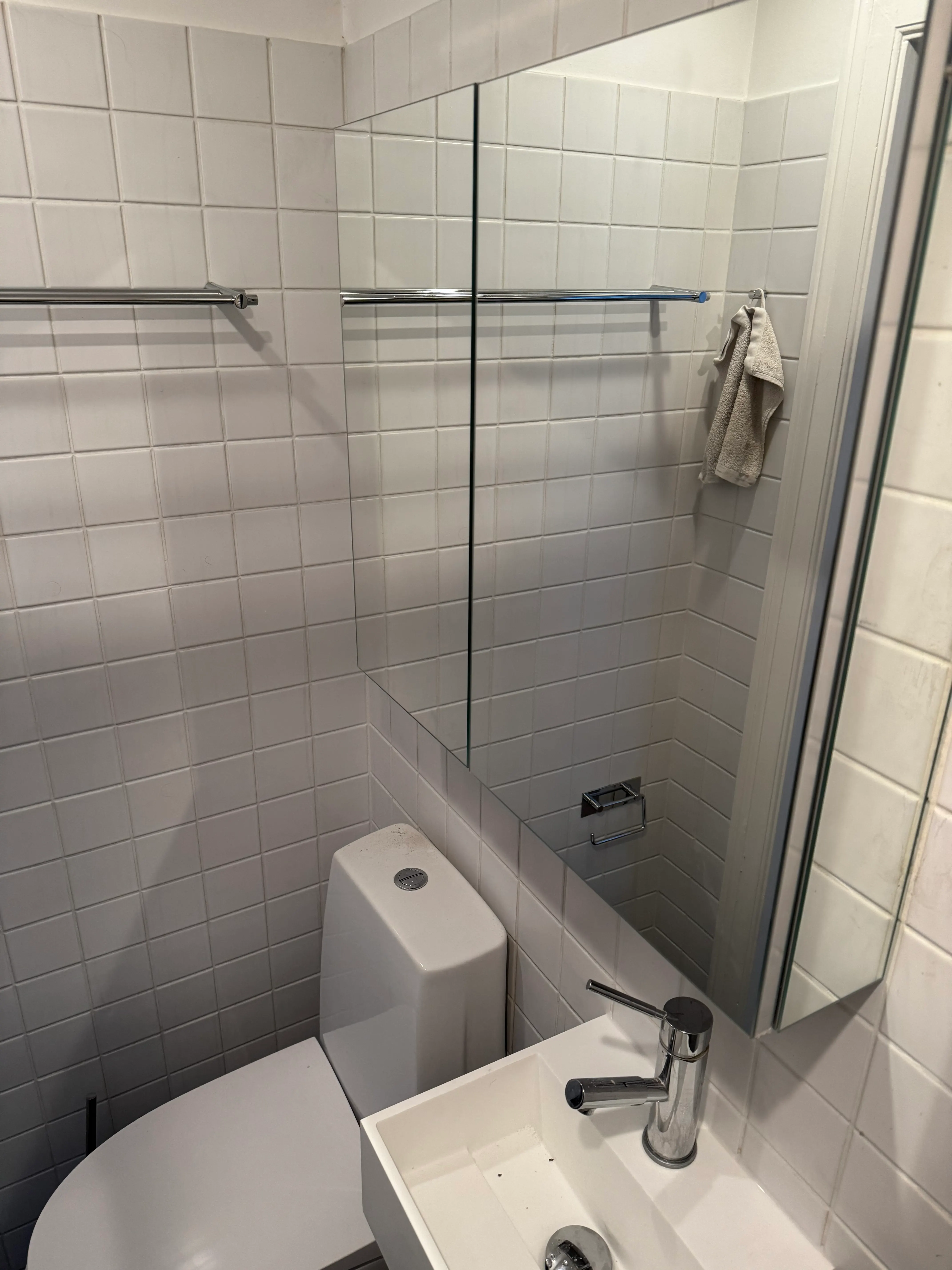 Final view of the compact bathroom after the sink and mirror cabinet replacement