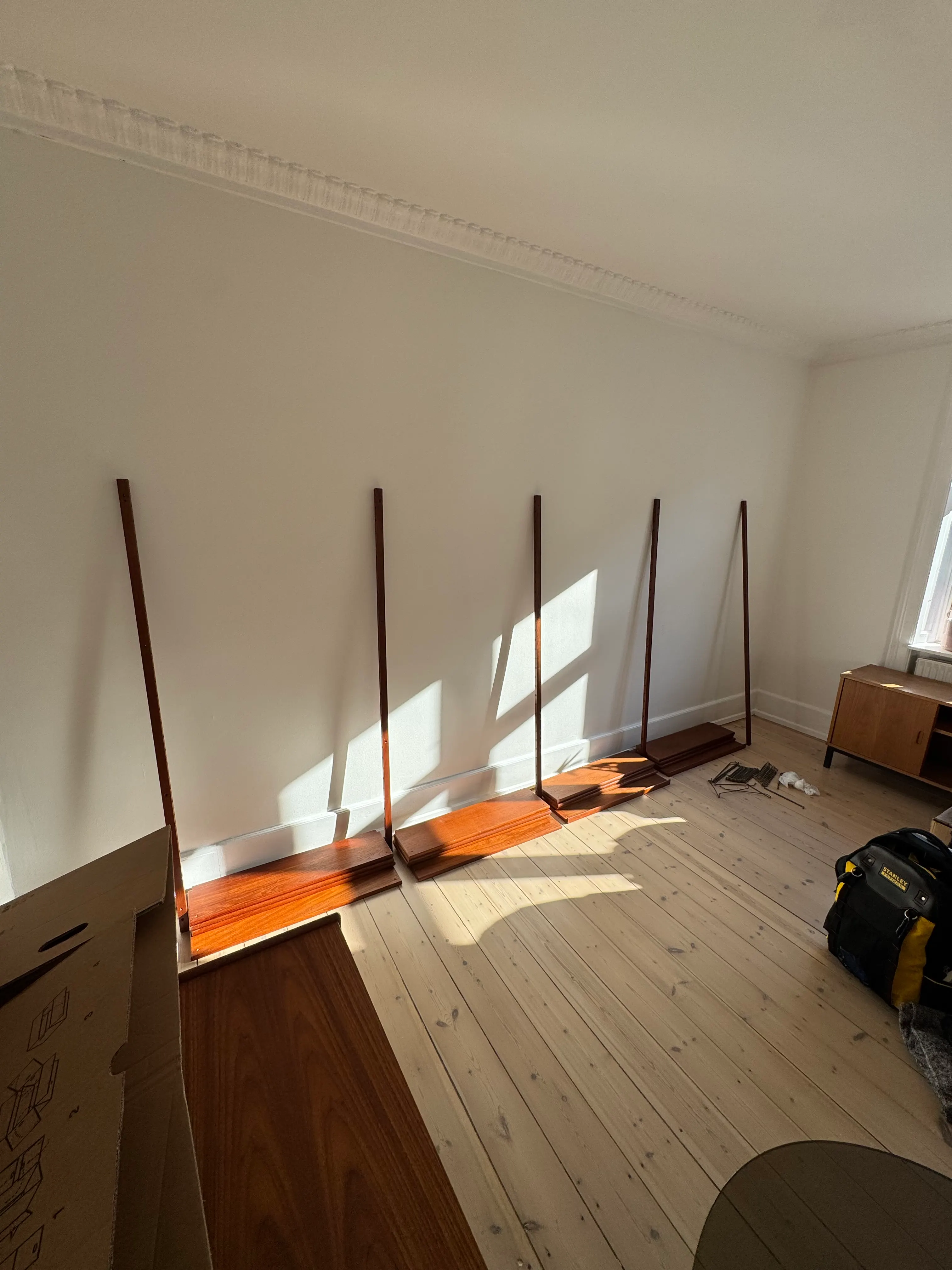 Five timber uprights positioned on a living room wall during a Cadovius Royal System installation
