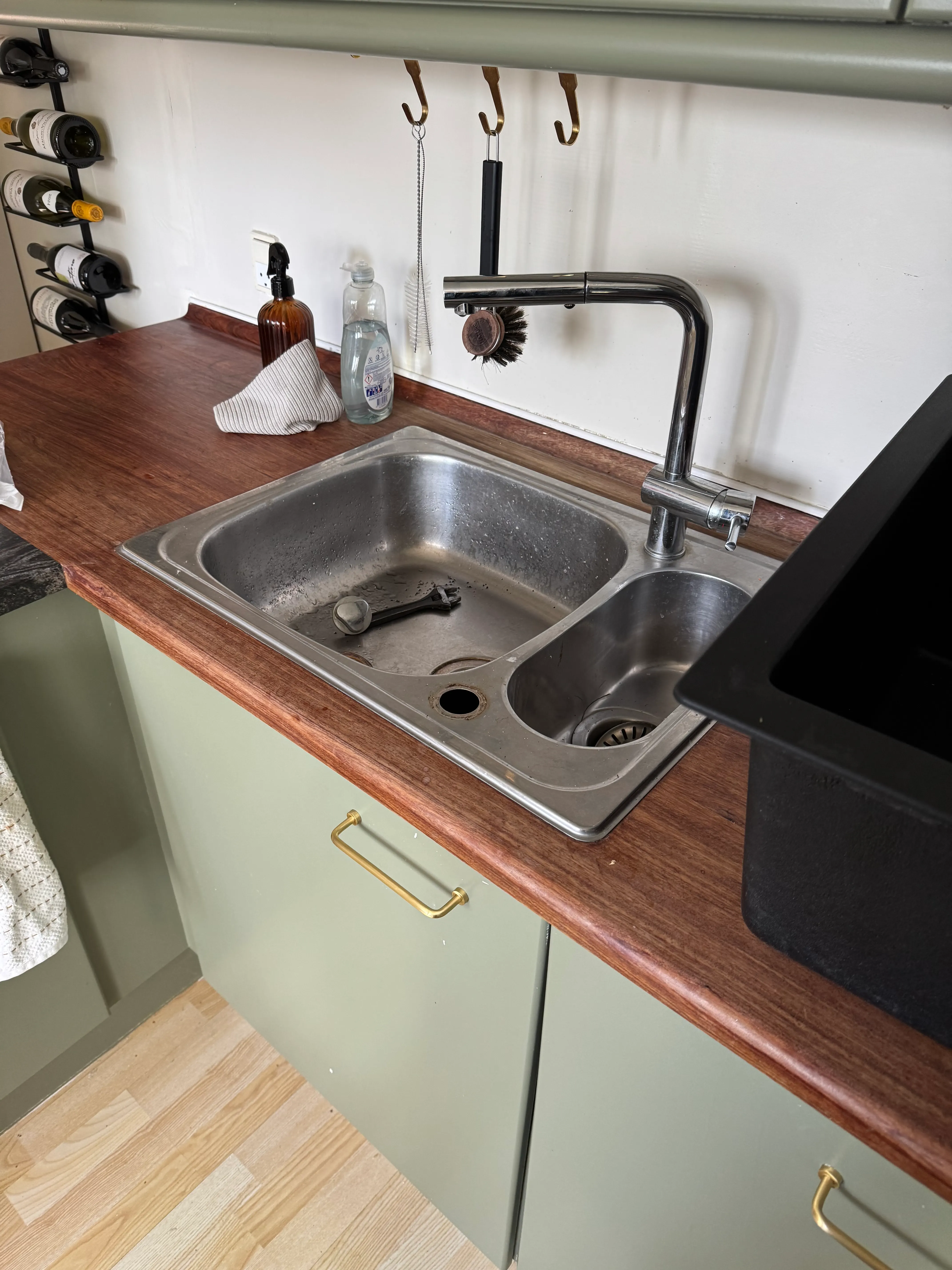 Existing double-bowl kitchen sink and chrome faucet set into the wooden countertop before replacement