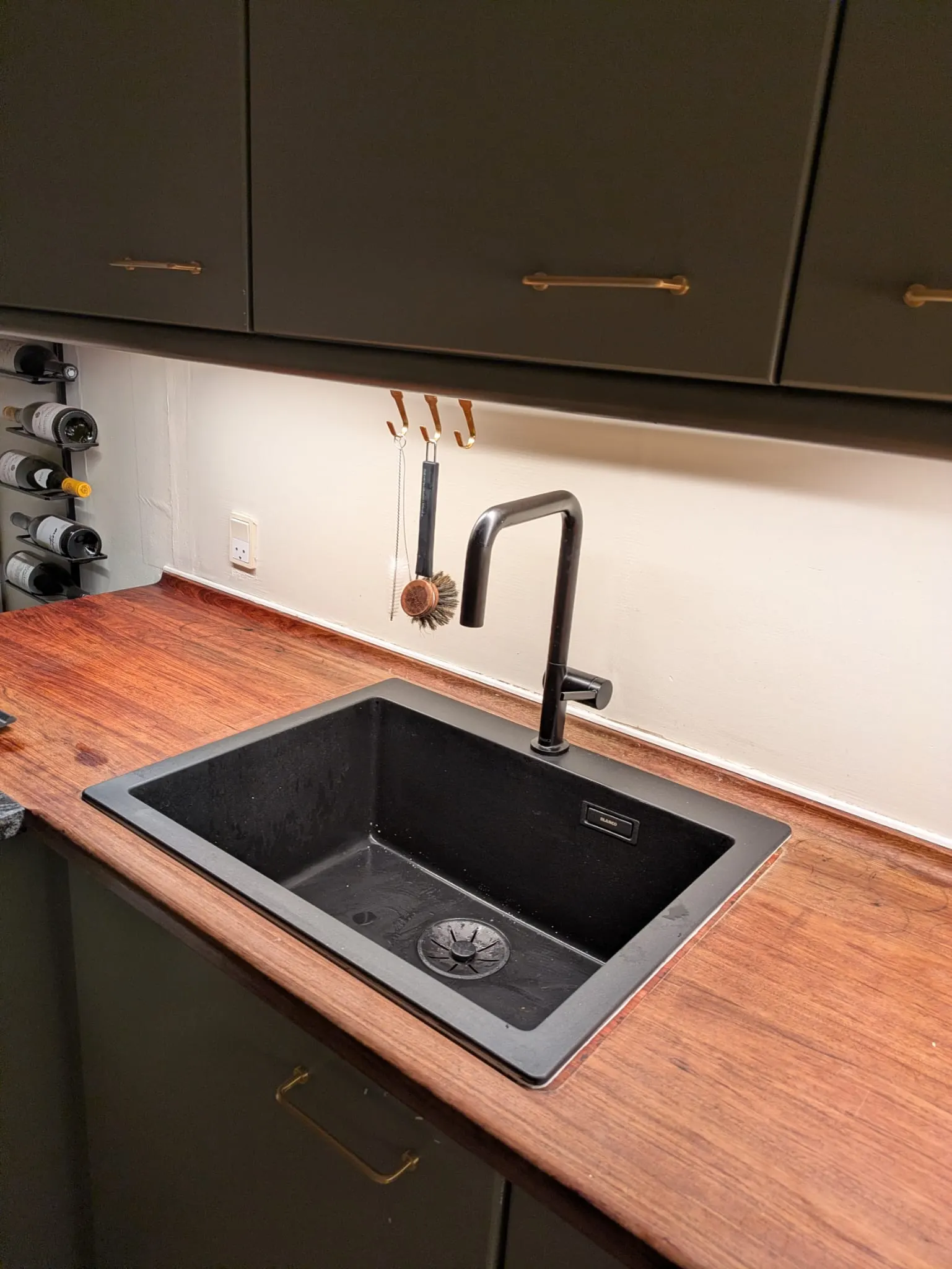 Black kitchen sink and matte-black faucet installed in an existing wooden countertop in Valby