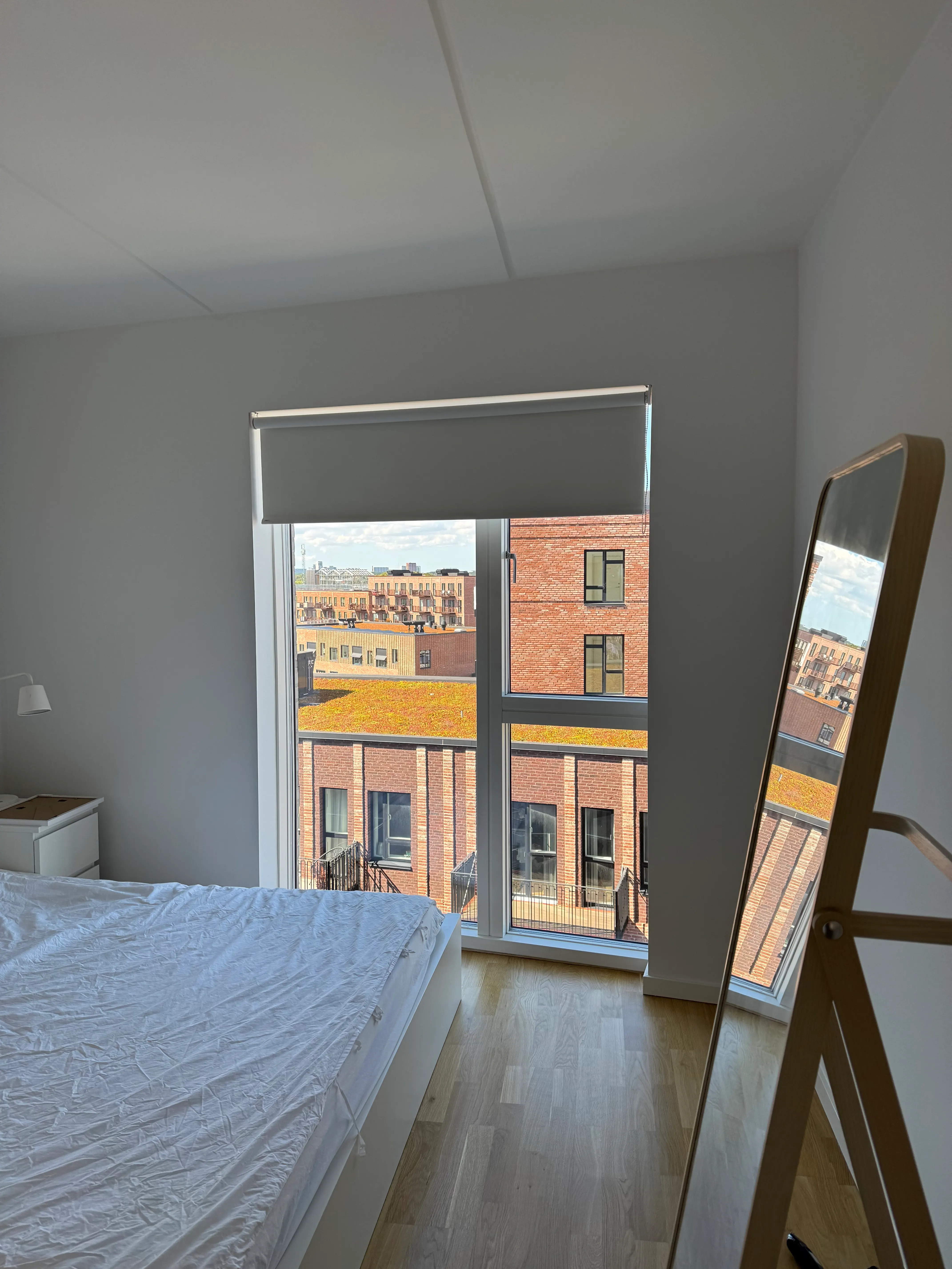 Roller blind installed inside a tall bedroom window recess in Valby